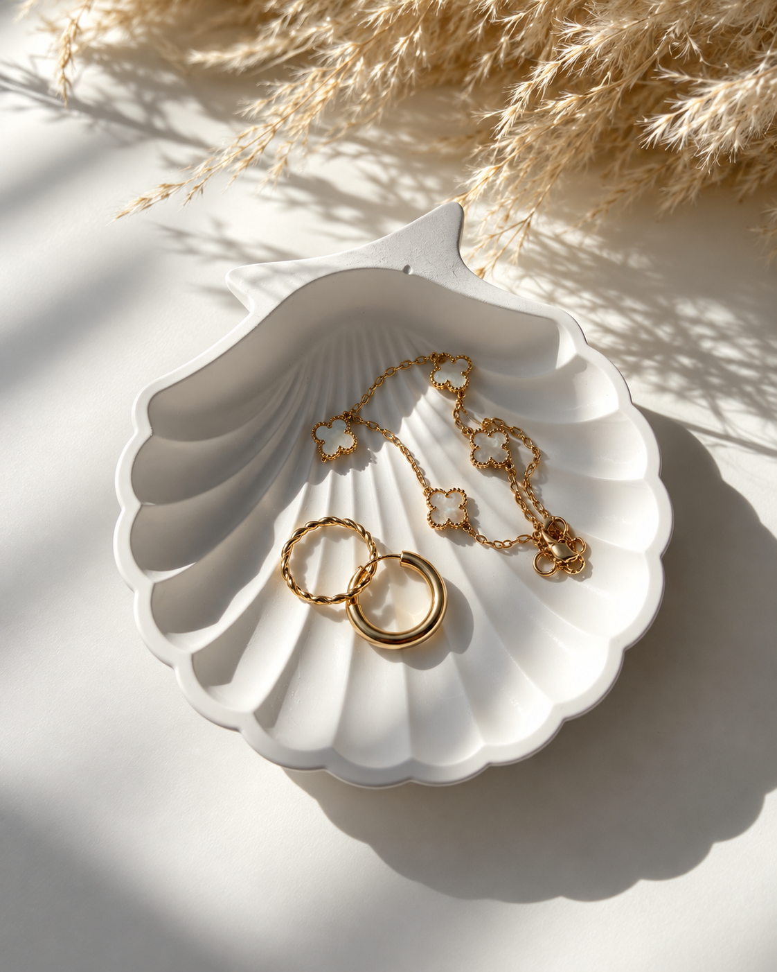 White shell jewellery dish styled with gold and pearl jewellery