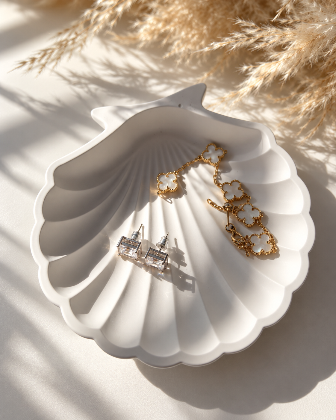 White shell jewellery dish with earrings and delicate gold jewellery