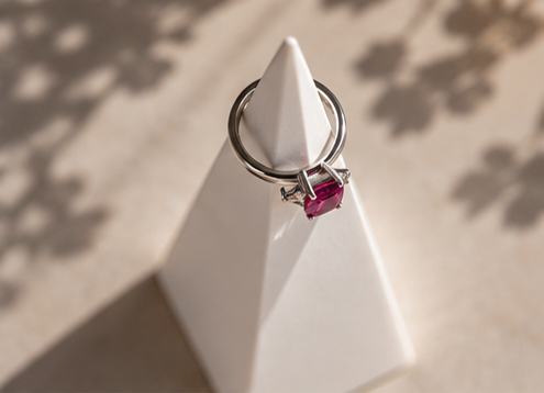 Stone ring cone holding a silver ring with pink gemstone